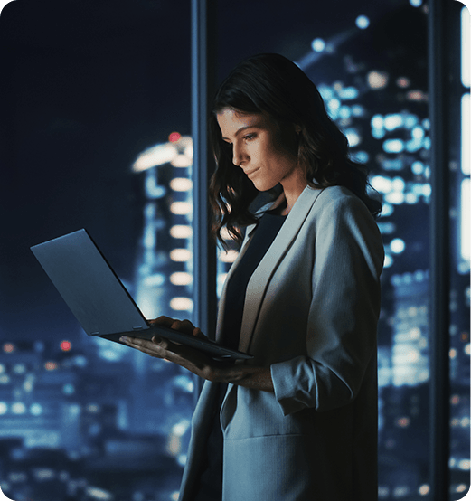 Businesswoman Using Laptop At Night In A City Office, Demonstrating Effective CPG Solution Implementation