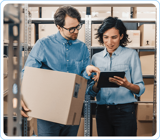 Warehouse Employees Using Tablet To Manage Supply Chain Inventory While Holding A Package In Storage Facility